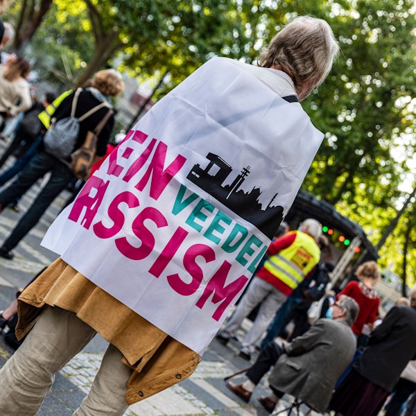Ein Mann steht mit einer Flagge, auf der "Kein Rassismus" steht