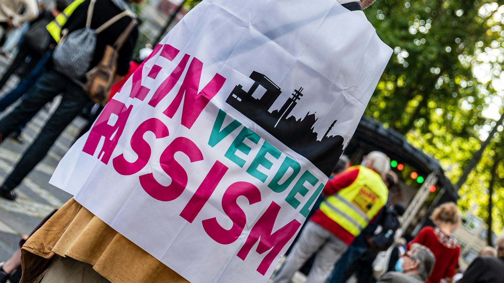 Ein Mann steht mit einer Flagge, auf der "Kein Rassismus" steht