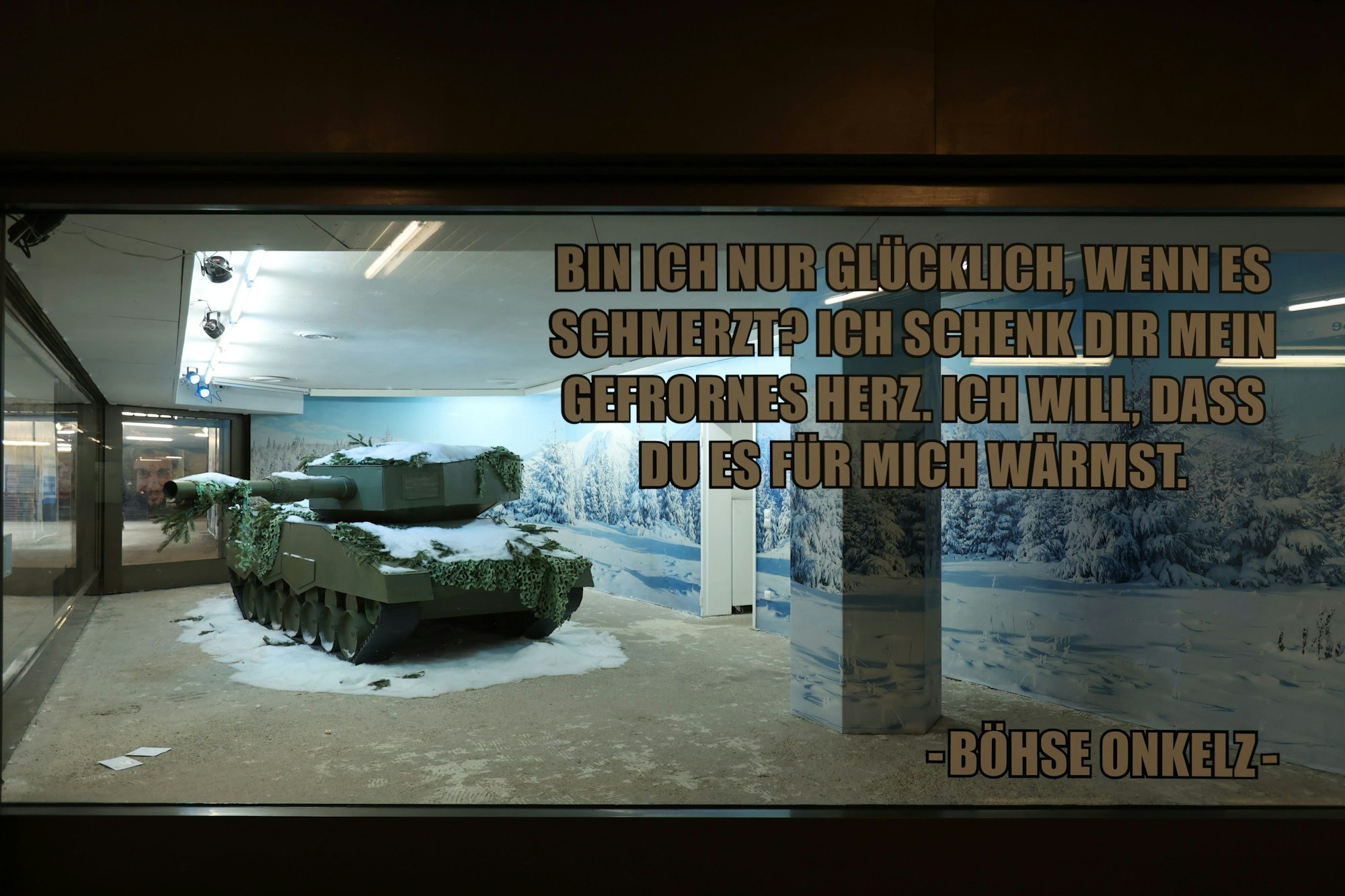 Hinter einem Zitat der Böhsen Onkelz ("Bin ich nur glücklich, wenn es schmerzt? Ich schenk dir mein gefrornes Herz. Ich will, dass du es für mich wärmst.) steht ein Papp-Panzer hinter Glas.