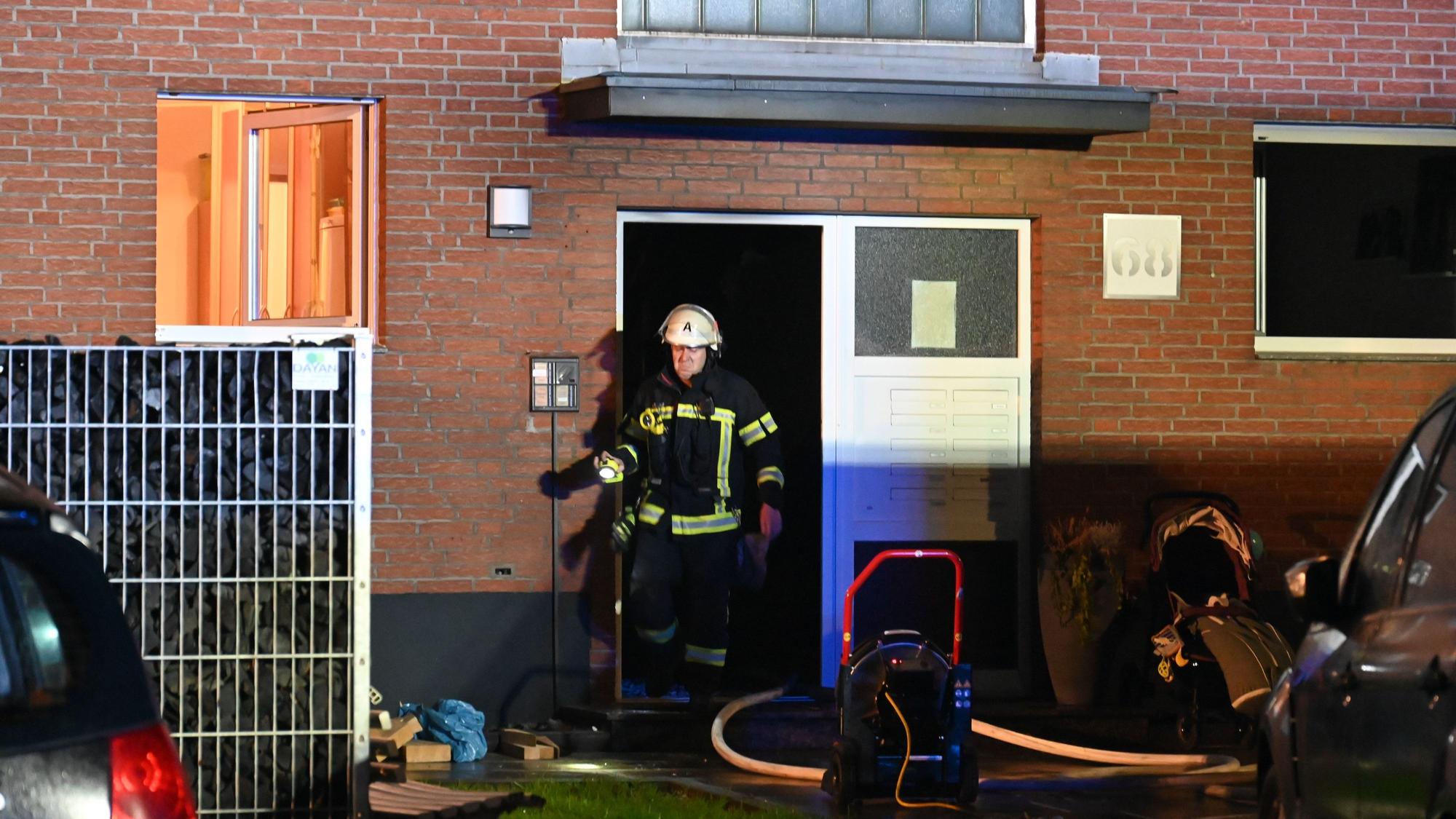 Ein Feuerwehrmann kommt aus einer Haustür. Ein Fenster im Erdgeschoss steht weit offen.
