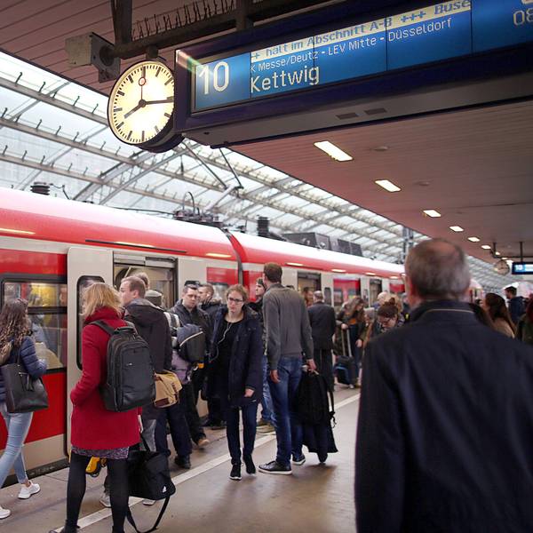 Pendler stehen im Hauptbahnhof Köln vor einer S-Bahn.