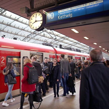 Pendler stehen im Hauptbahnhof Köln vor einer S-Bahn.
