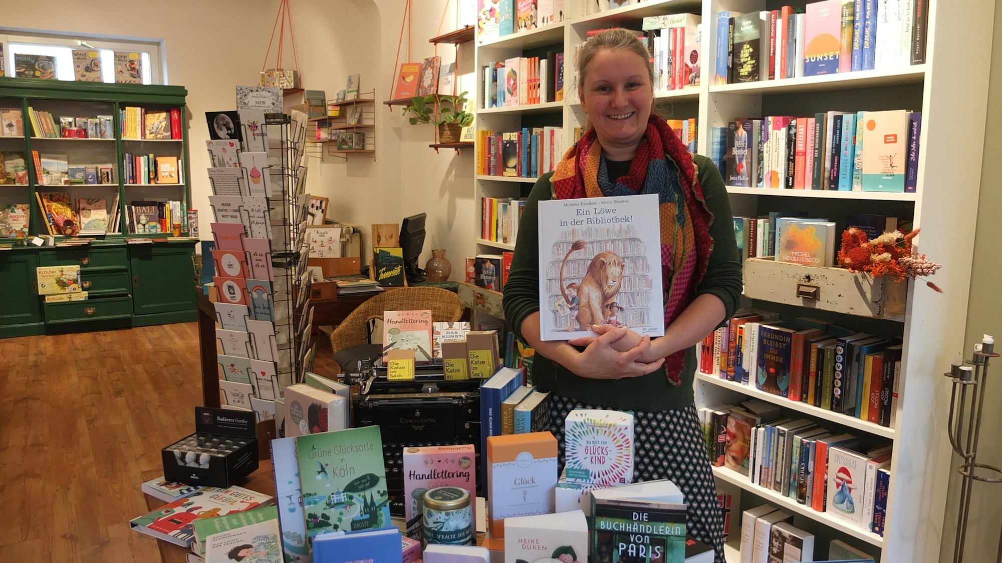 Eine Frau steht in einer Buchhandlung mit einem Kinderbuch in der Hand.
