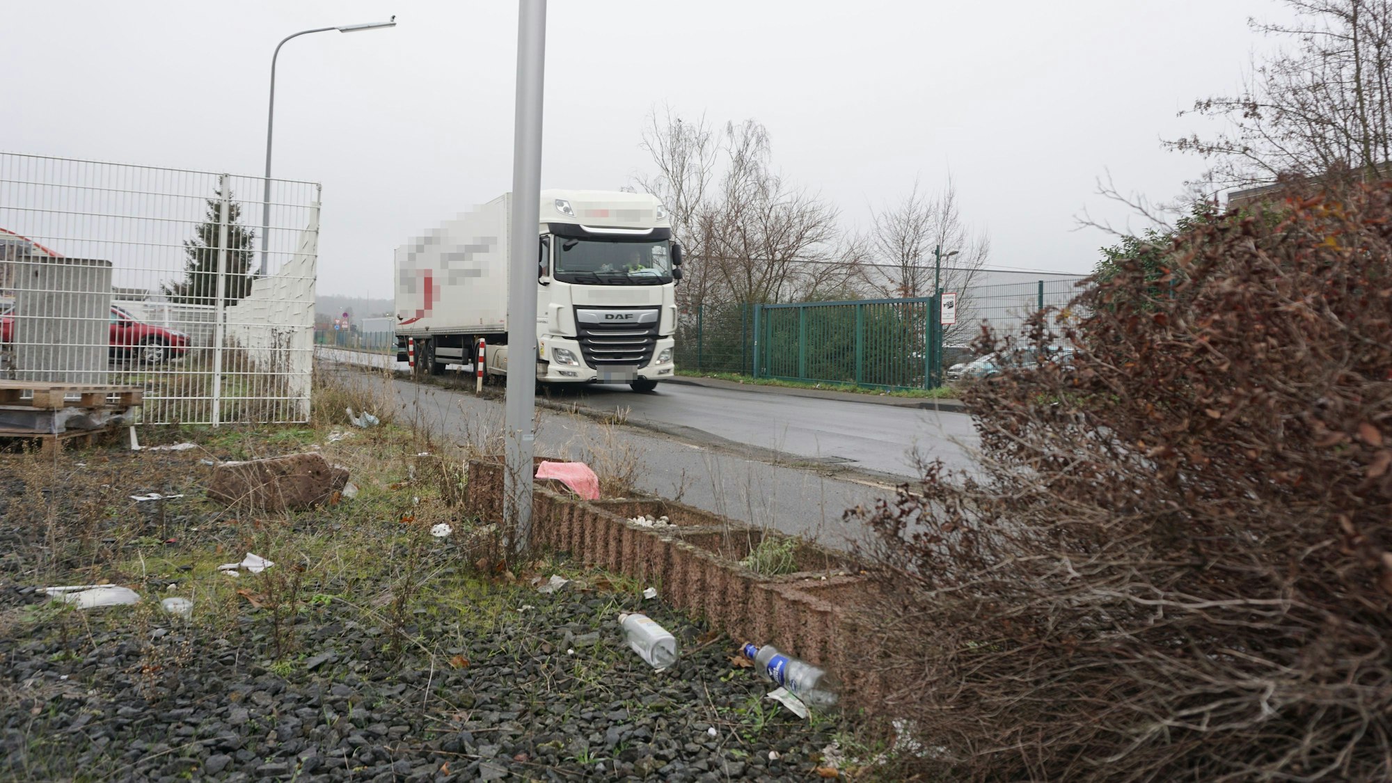 Ein weißer Lkw fährt über die Robert-Bosch-Straße. Neben der Straße liegt Müll.