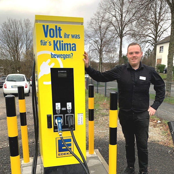 Manuel Marquardt, stellvertretender Leiter des Edeka-Marktes in Witzhelden, steht neben der gelben Elektro-Ladesäule auf dem Parkplatz an der Solinger Straße.