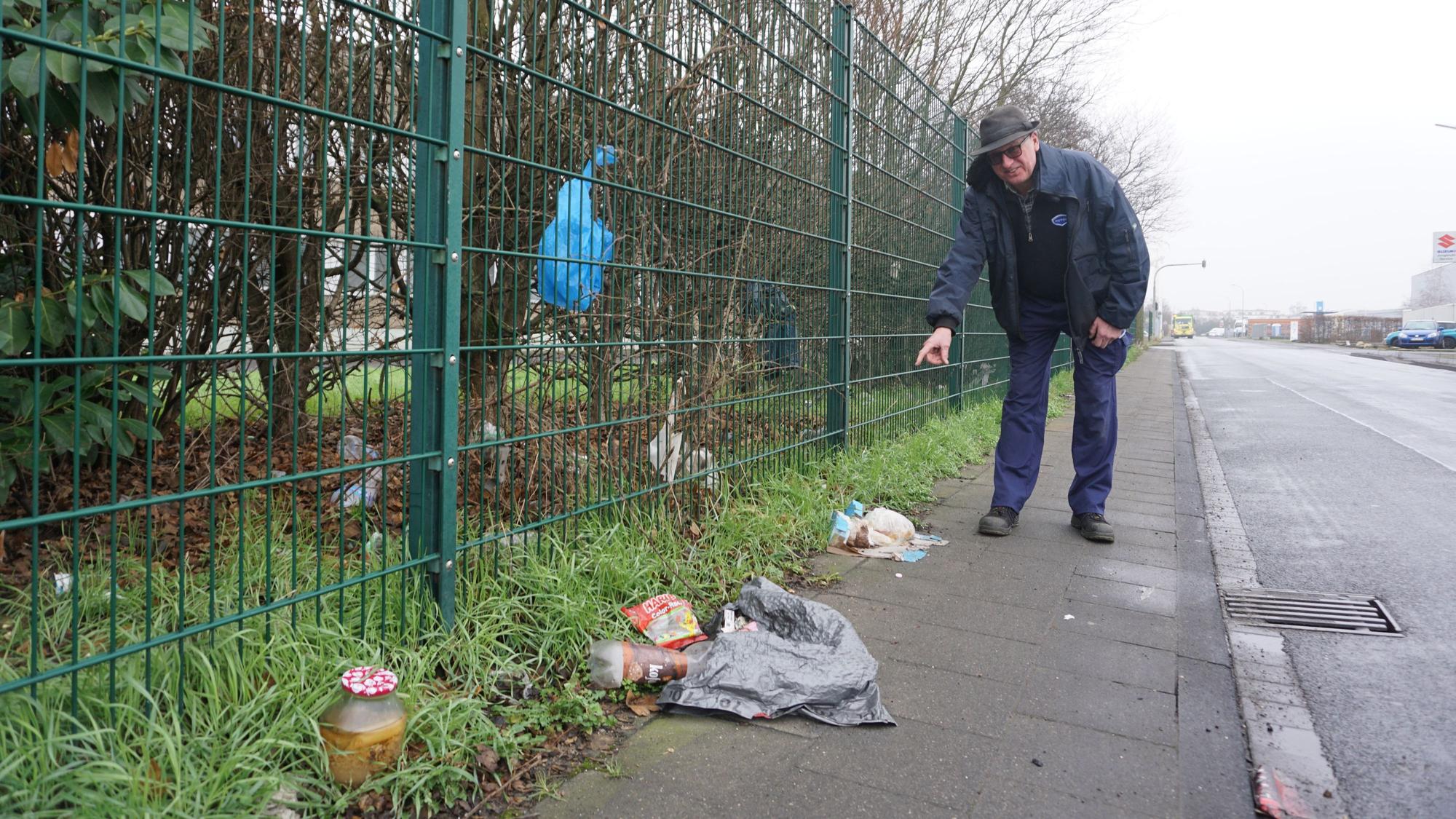 Peter Jungbluth führt durch die verdreckte Robert-Bosch-Straße in weilerswist und deutet auf den Müll.