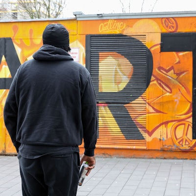 Der 19-jährige Chris schaut auf eine mit Graffiti besprühte Mauer. Es ist nur sein Rücken zu sehen, Chris möchte anonym bleiben.