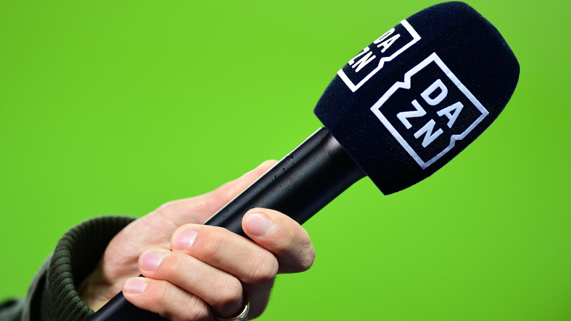 Die Hand eines Reporters hält bei einem Interview vor dem Spiel ein Mikrofon mit der Aufschrift DAZN.
