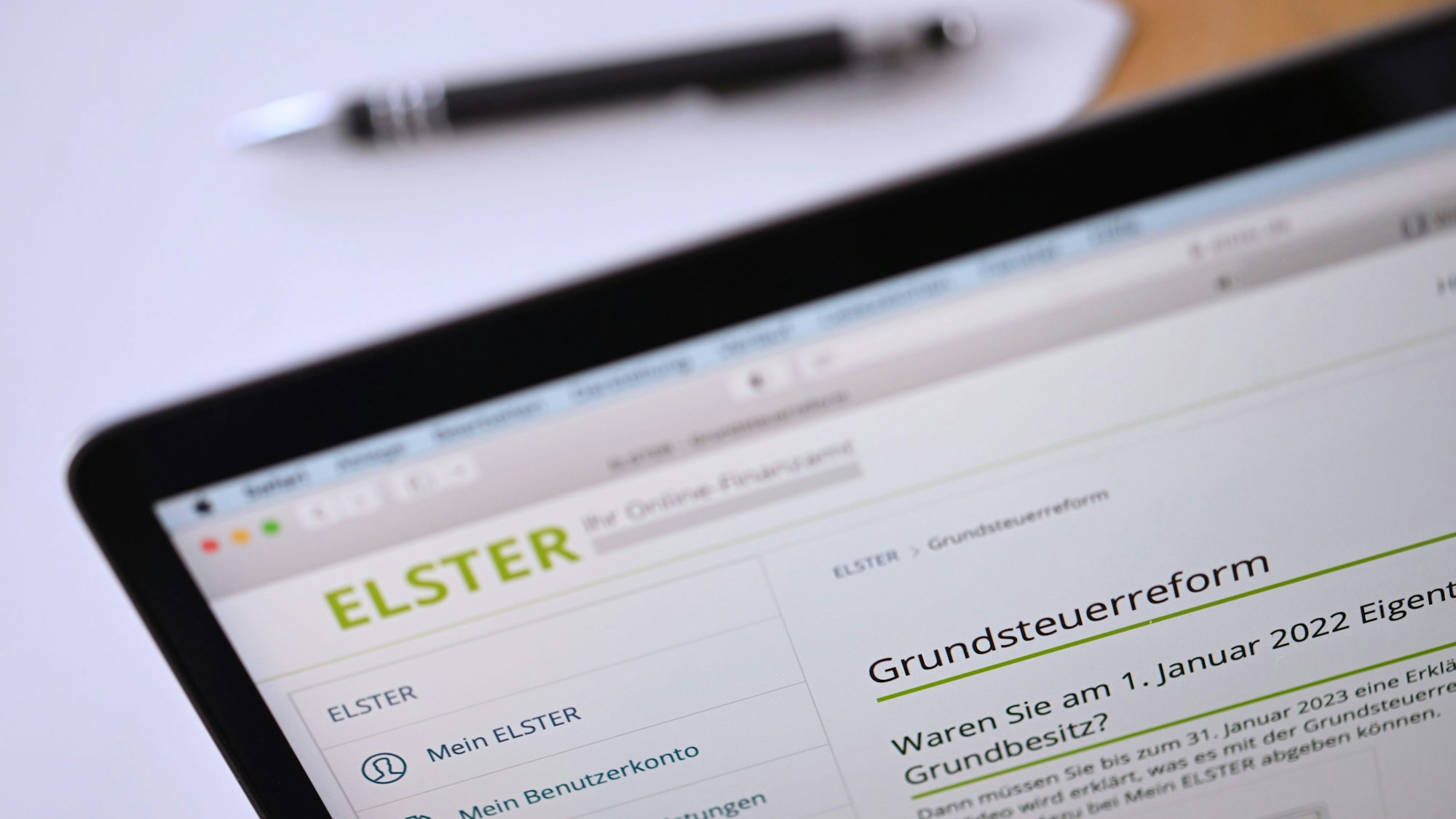 Auf einem geöffneten Laptop-Bildschirm ist eine Seite der „Elster“-Steuerplattform geöffnet, die Informationen über die Grundsteuerreform enthält.