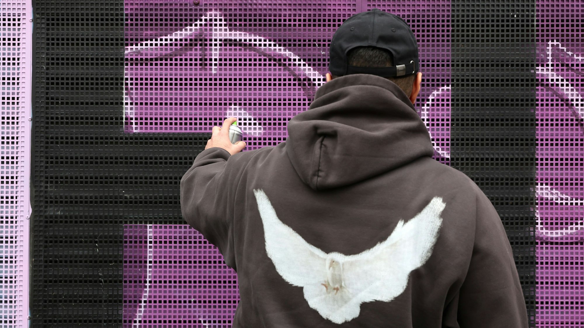 Der 19-jährige Chris besprüht eine Wand mit Graffiti.