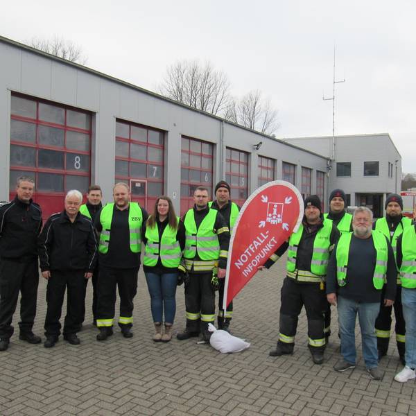 Eine Gruppe von Feuerwehrleuten steht vor ihrer Wache.