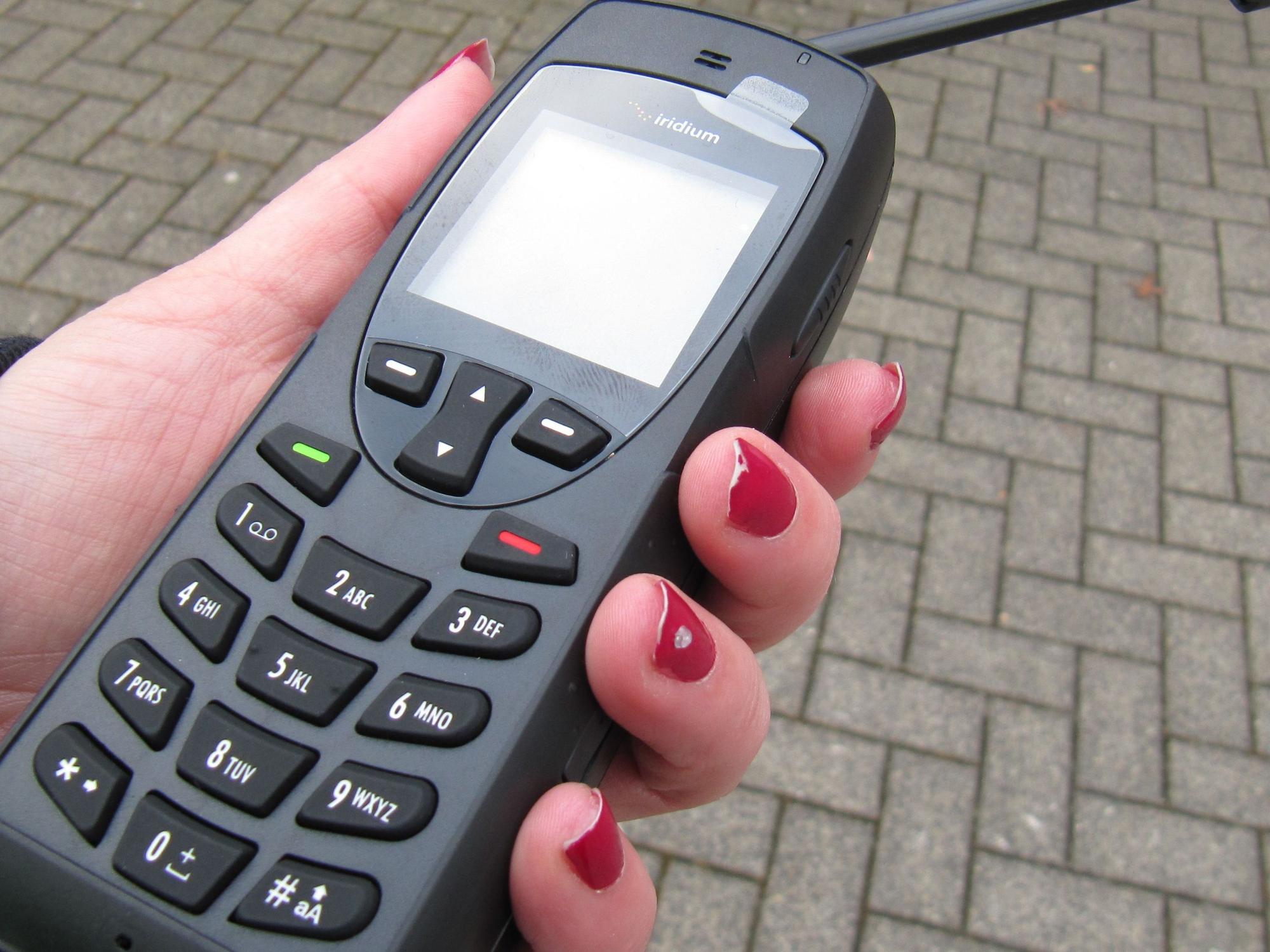 Eine Frauenhand hält ein Satellitentelefon.