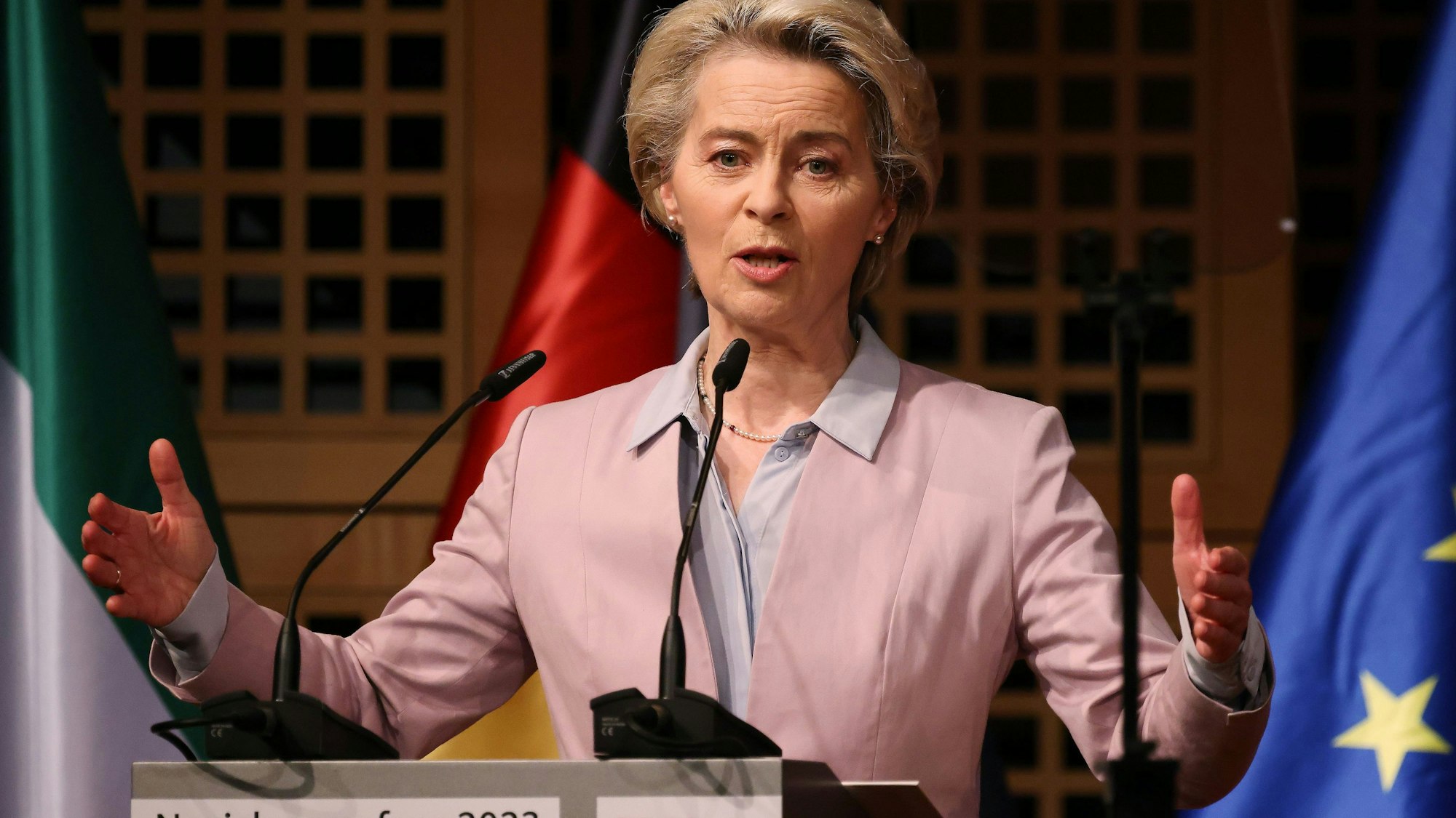 Ursula von der Leyen steht am Rednerpult und gestikuliert mit den Händen. Im Hintergrund sind die Flaggen von Nordrhein-Westfalen, Deutschland und der Europäischen Union.