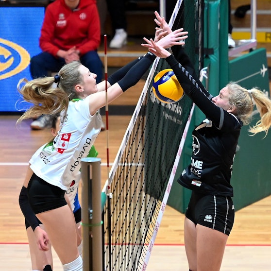 Zwei Volleyballspielerinnen kämpfen am Netz um einen Punkt.