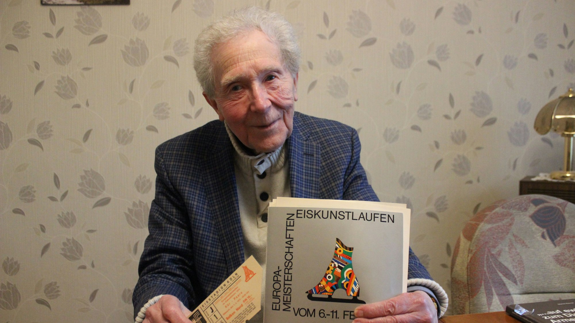 Karl Wingenfeld hält das Programmheft der Eiskunstlauf-EM 1973 in die Kamera.