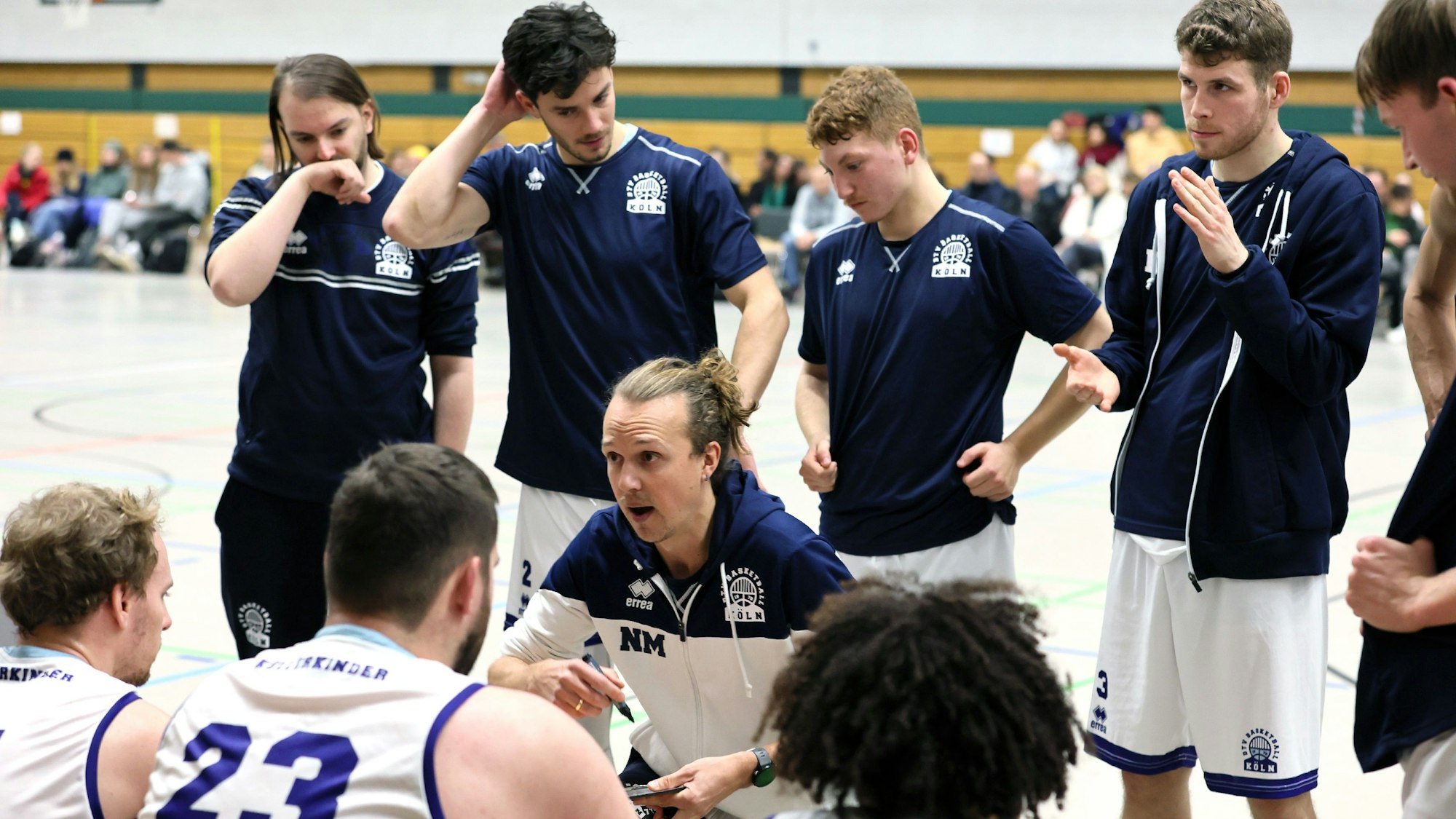 Ein Basketballtrainer bespricht sich mit seinem Team in einer Auszeit.