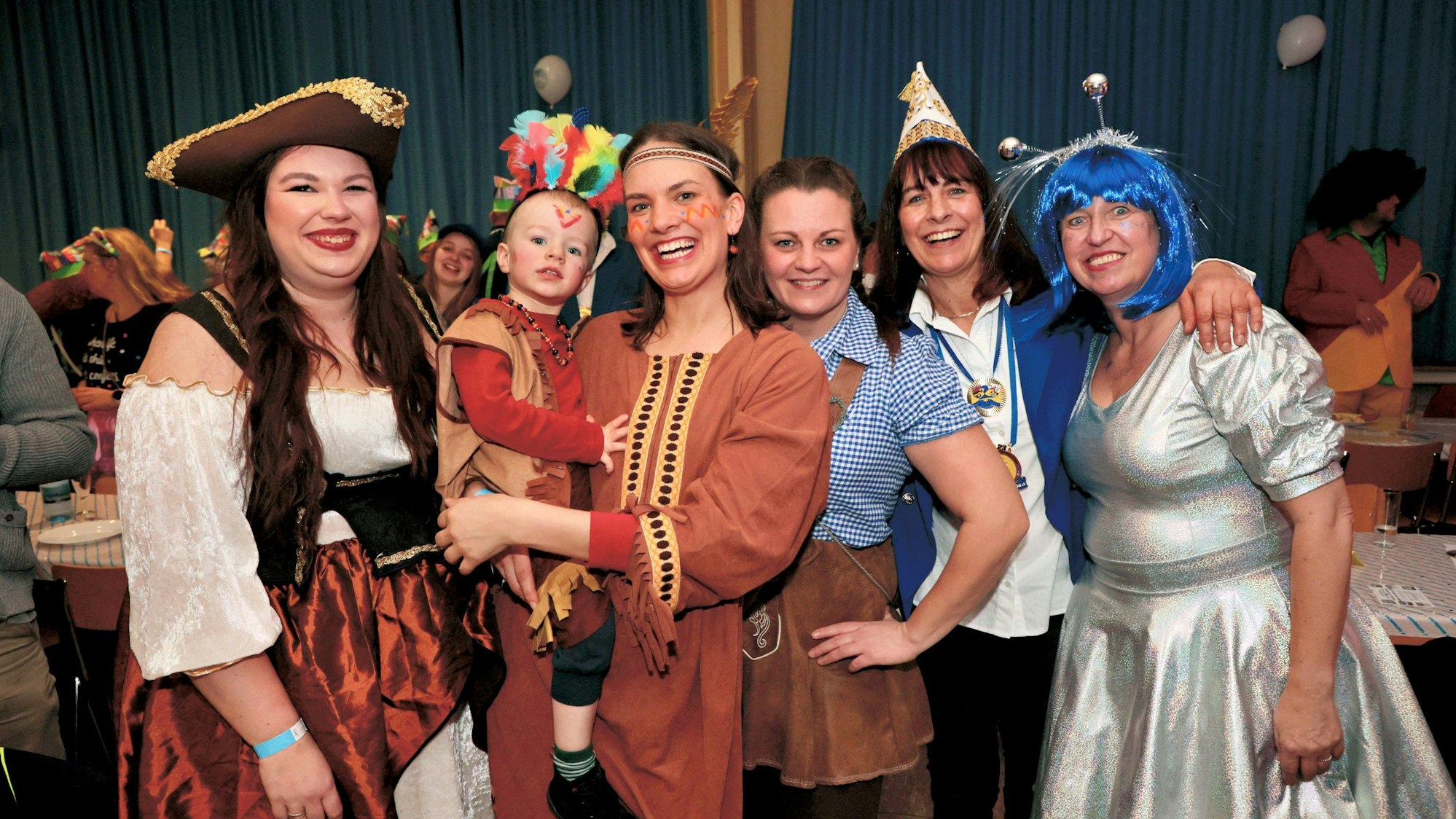 Kostümierte Frauen und ein Kind lachen in die Kamera