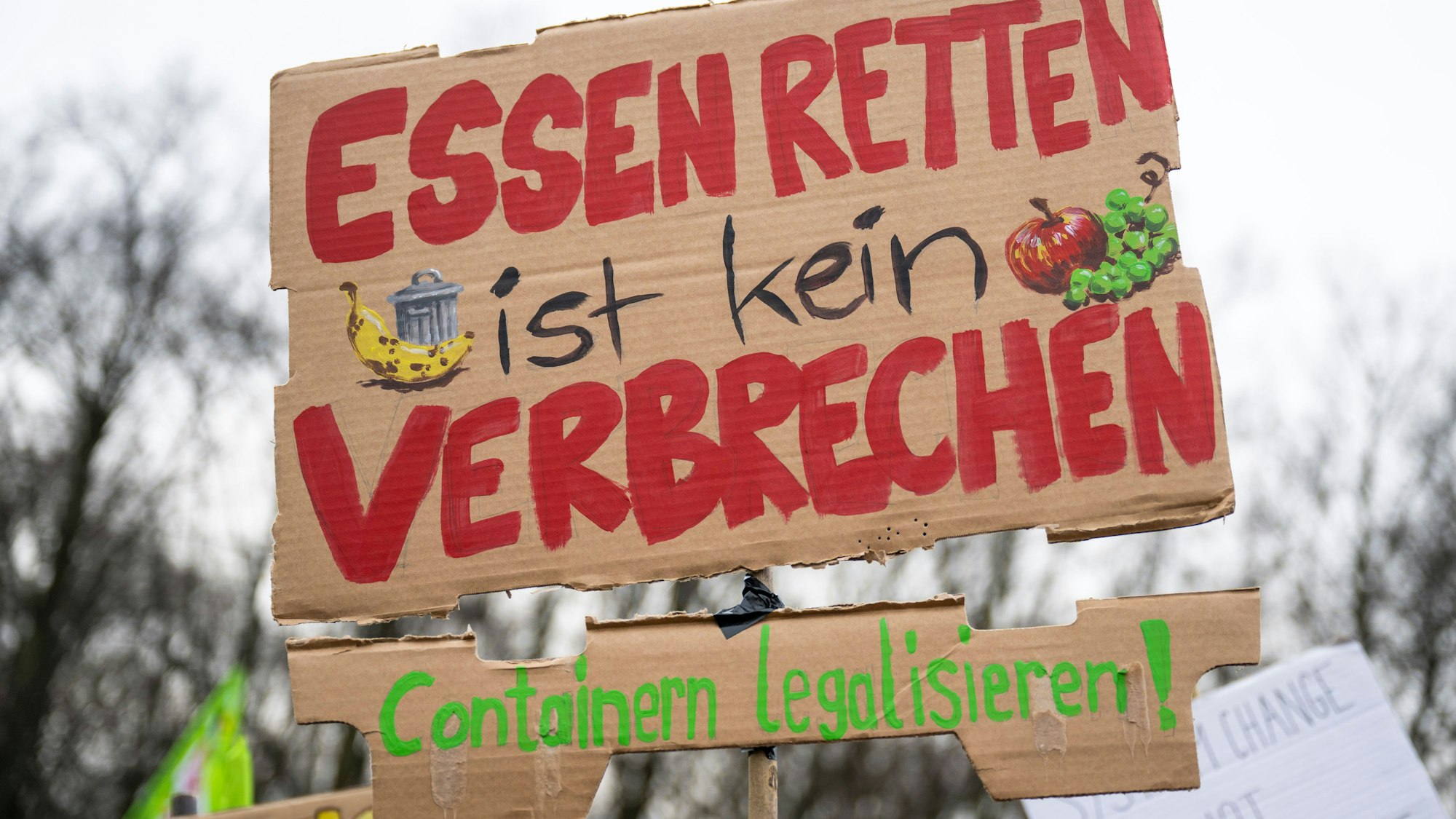 Bei einer Demonstration trägt ein Teilnehmer vor dem Brandenburger Tor ein Plakat mit der Aufschrift „Essen retten ist kein Verbrechen - Containern legalisieren!“.