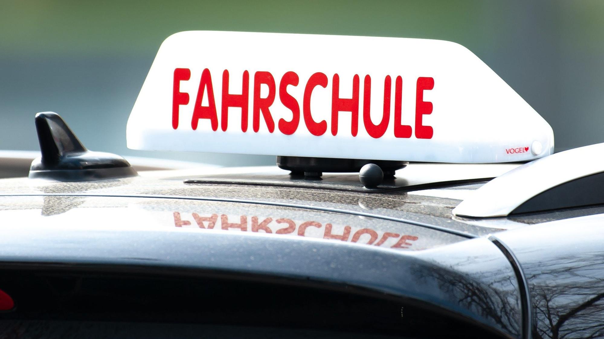 Ein Schild mit der Aufschrift „Fahrschule“ ist auf einem Auto befestigt.