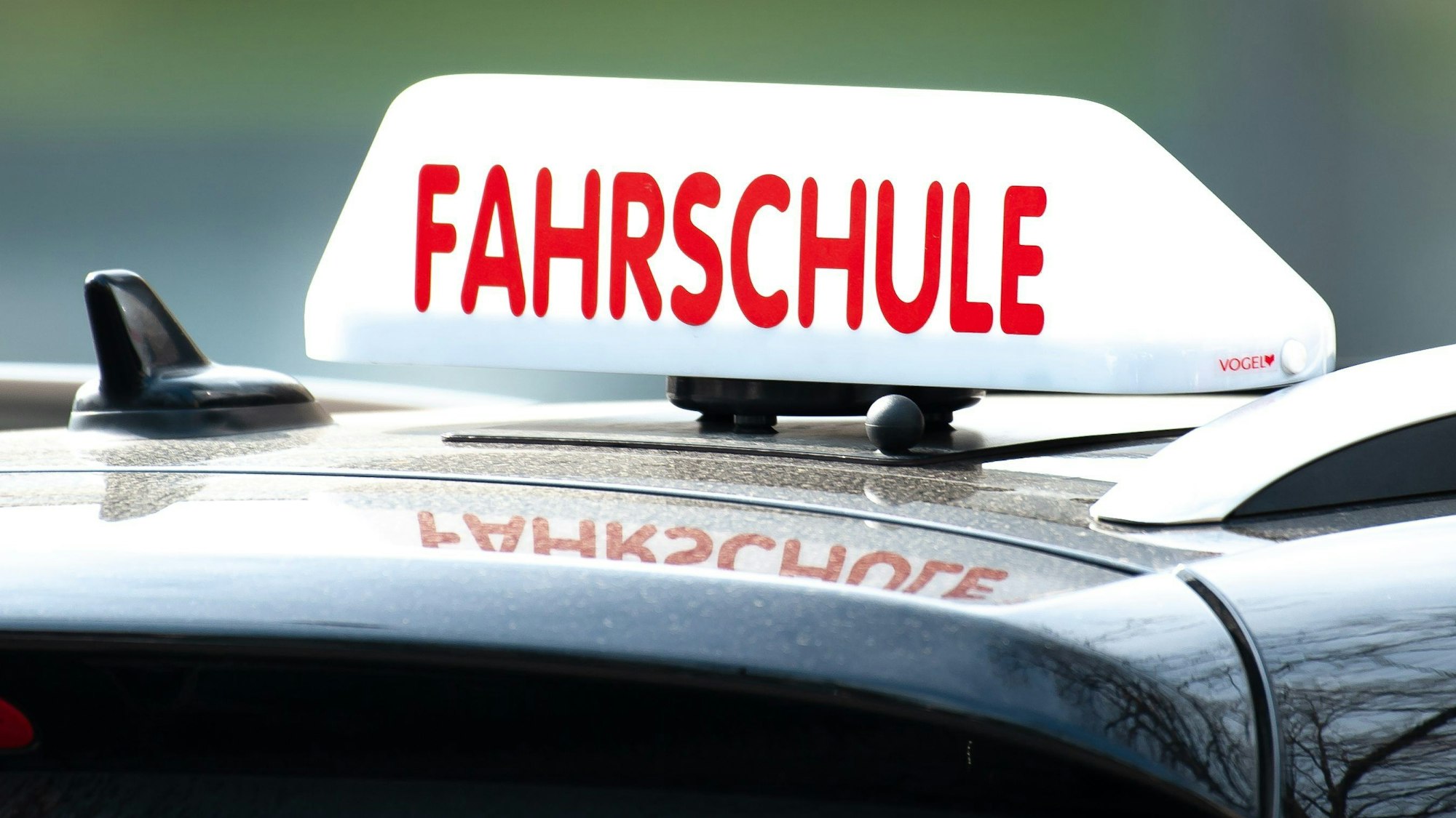 Ein Schild mit der Aufschrift „Fahrschule“ ist auf einem Auto befestigt.