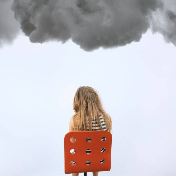 Ein Mädchen sitzt auf einem roten Stuhl unter dunklen Wolken.