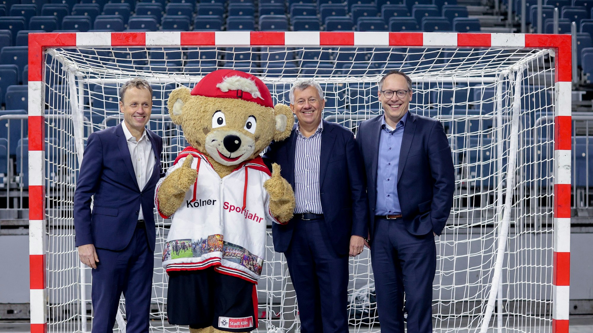 Die Handballmanager Frank Bohmann, Michael Wiederer und Mark Schober stehen während der Pressekonferenz auf dem Spielfeld.