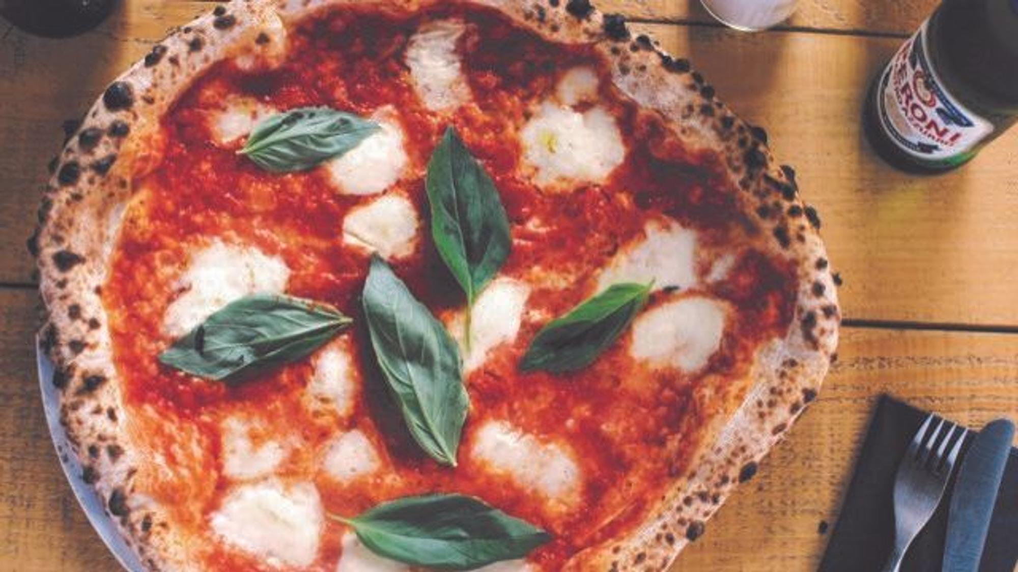 Eine Pizza mit Mozzarella und Basilikum