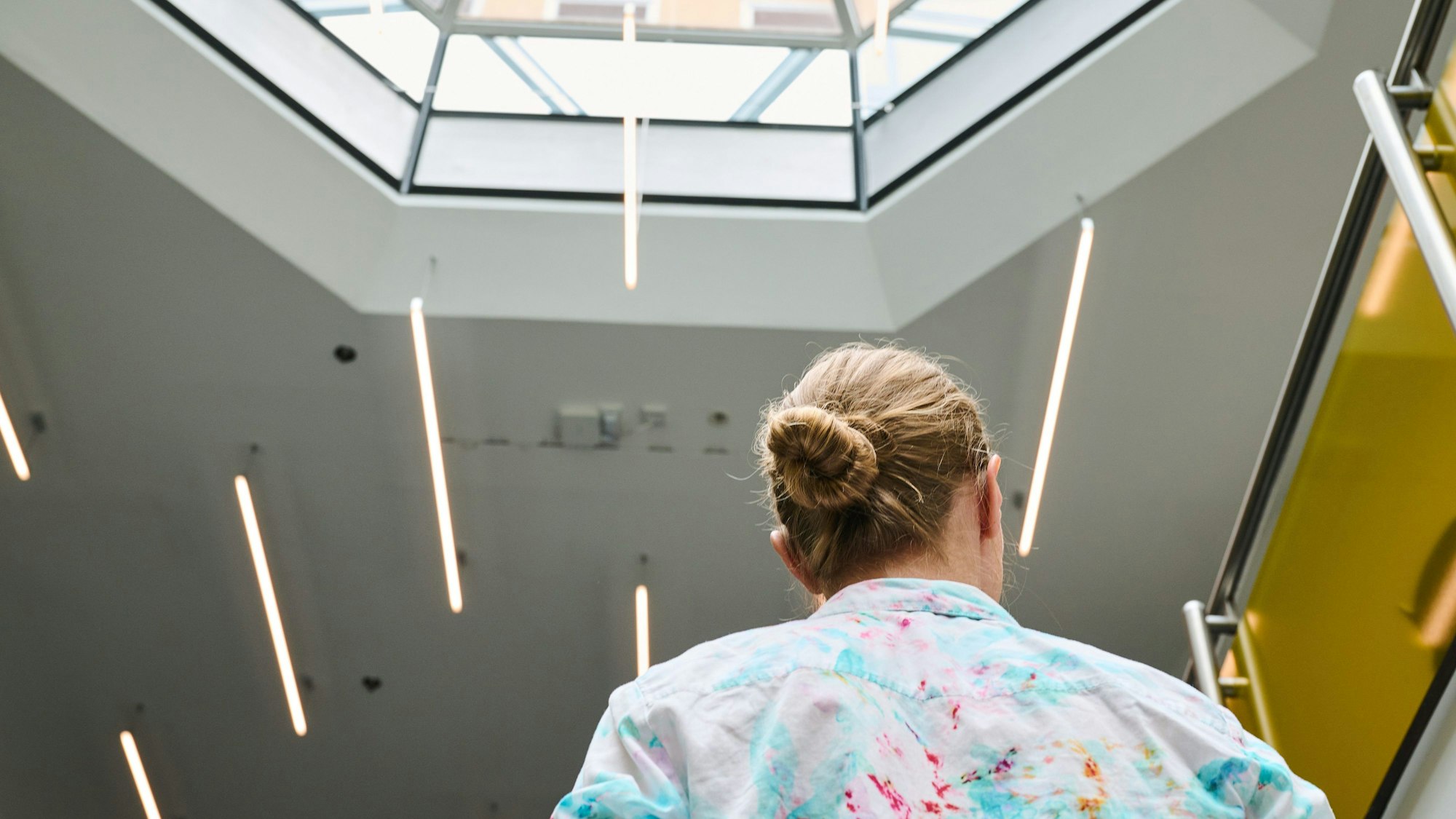 Es ist eine Frau von hinten zu sehen. Sie befindet sich auf der Arbeit.