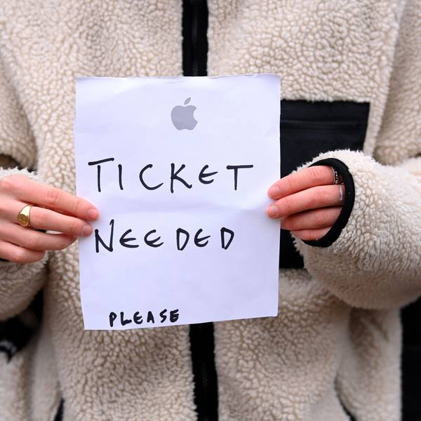 Eine Person hält einen Zettel in der Hand, auf den sie „Ticket needed – please“ geschrieben hat.