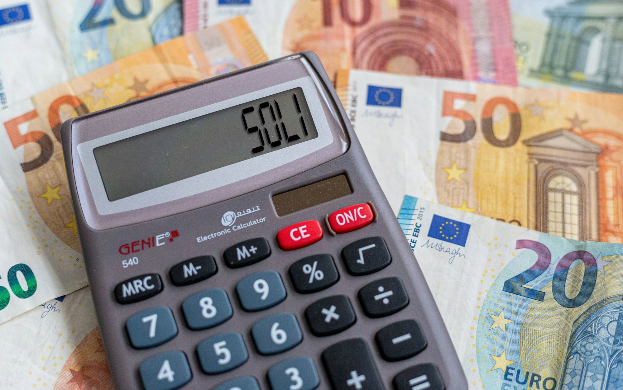 Ein Taschenrechner liegt auf Geldscheinen.