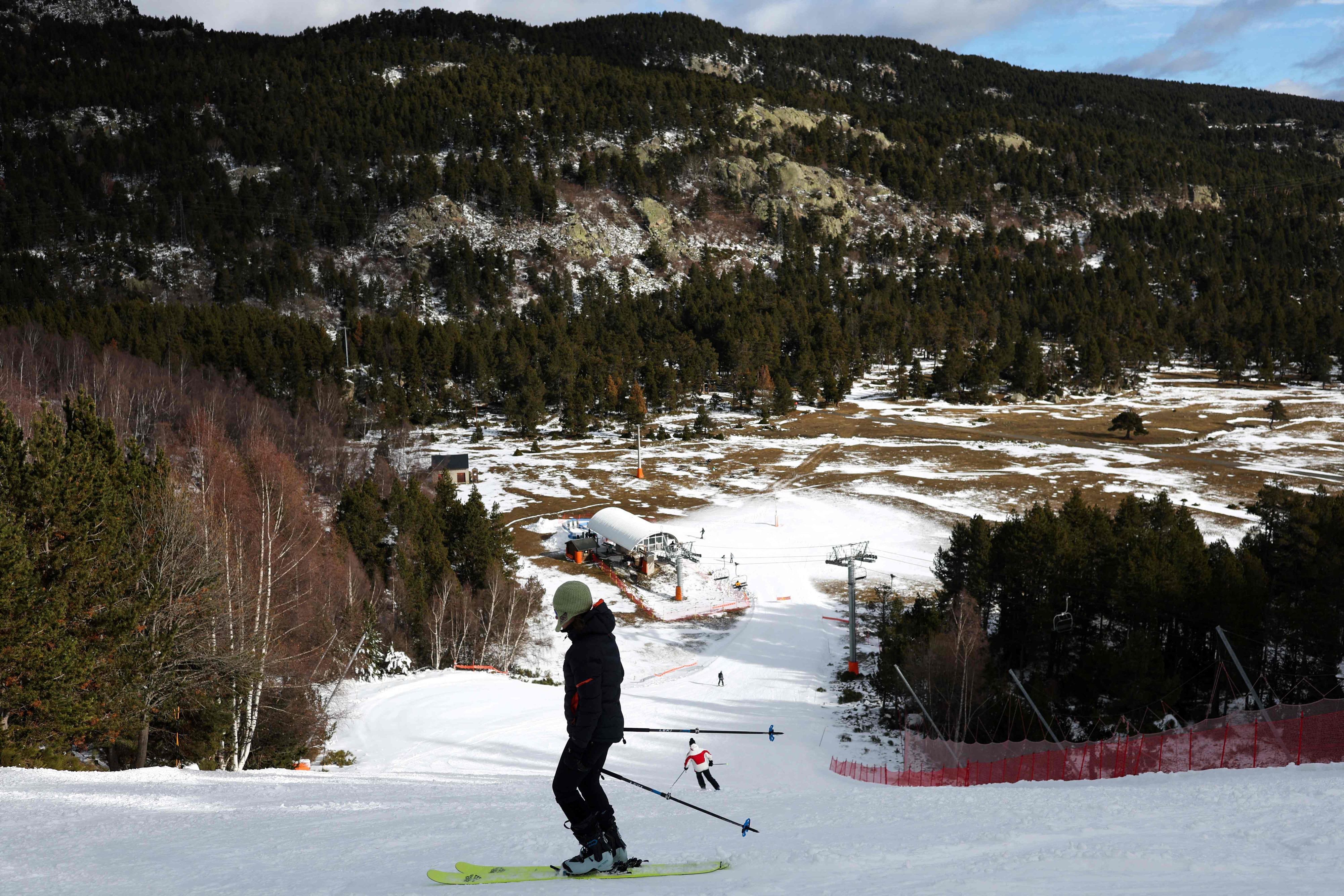 Es ist ein Skifahrer zu sehen, der auf der Piste steht und bergab schaut.
