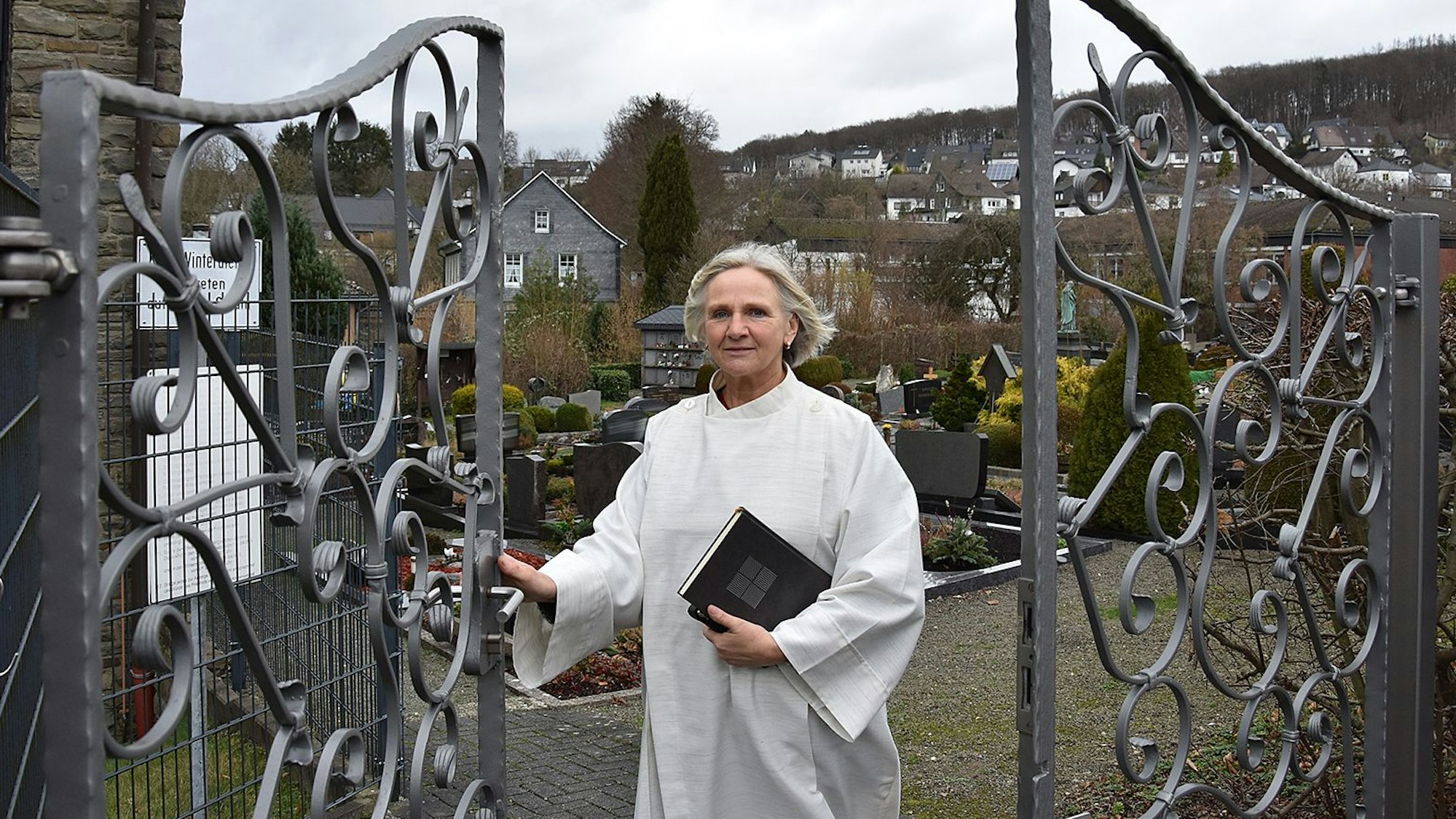 Mechthild Heide steht an einem Friedhofstor.