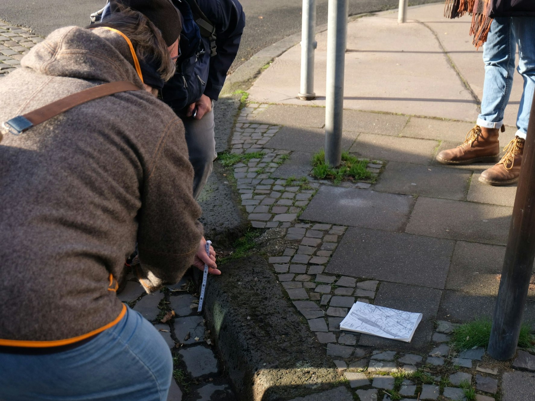 Während der Tour präsentieren zwei Anwohner die hohen Bürgersteige im Veedel, die für Rollstuhlfahrer ein Problem sein können.