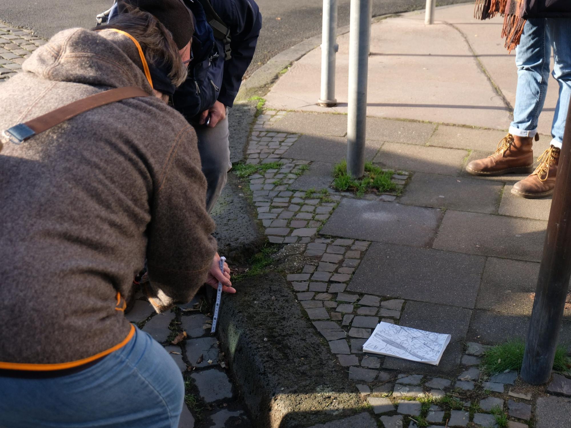 Während der Tour präsentieren zwei Anwohner die hohen Bürgersteige im Veedel, die für Rollstuhlfahrer ein Problem sein können.