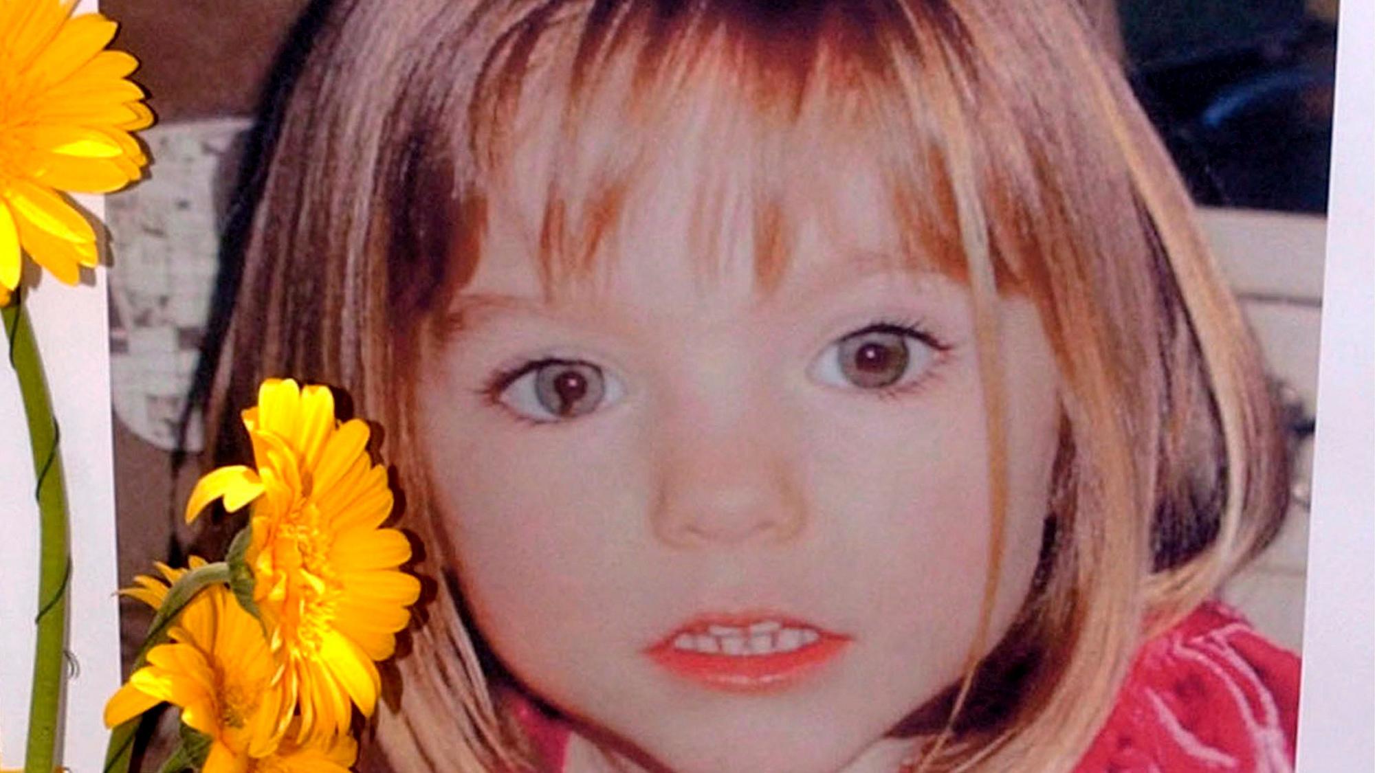 Blumen stehen vor einem Bild, das die verschwundene Madeleine McCann (Maddie) auf einem Foto zeigt, das ihre Eltern im Zusammenhang mit dem Verschwinden des Kindes am 3. Mai 2007 veröffentlich haben.