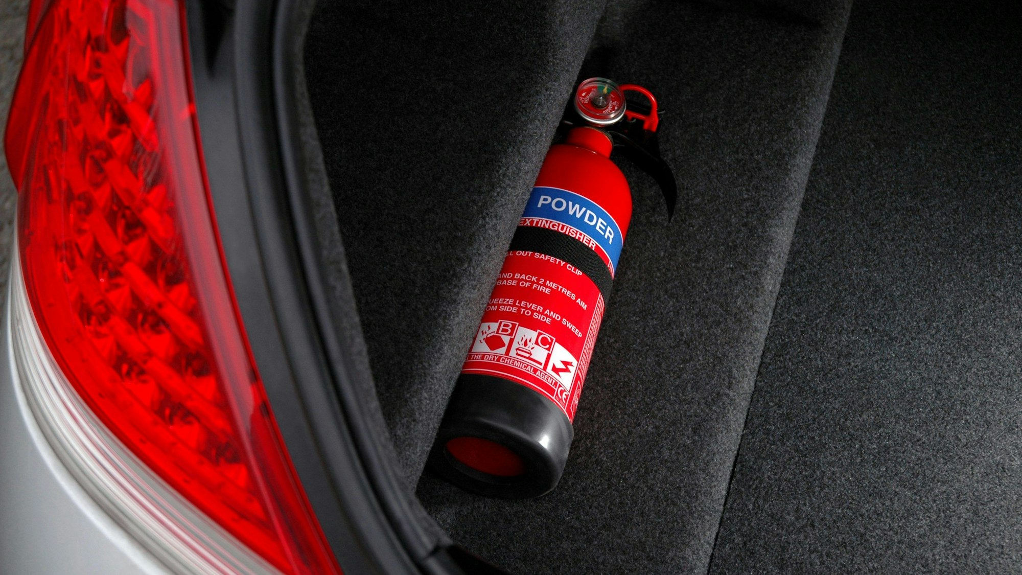 Ein Feuerlöscher liegt in einem Kofferraum.
