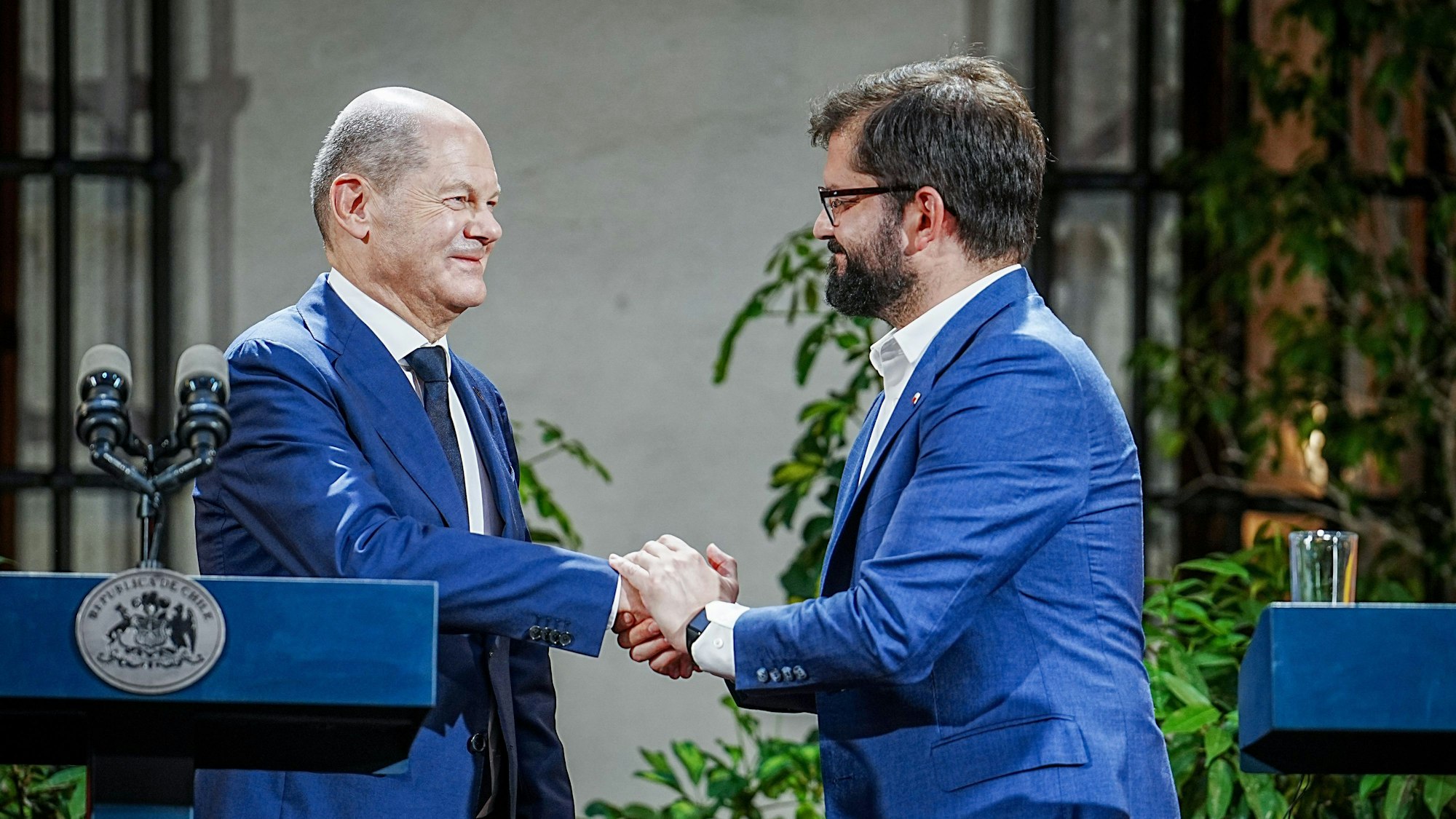 Es sind Olaf Scholz und Gabriel Boric zu sehen, wie sie sich die Hände schütteln.
