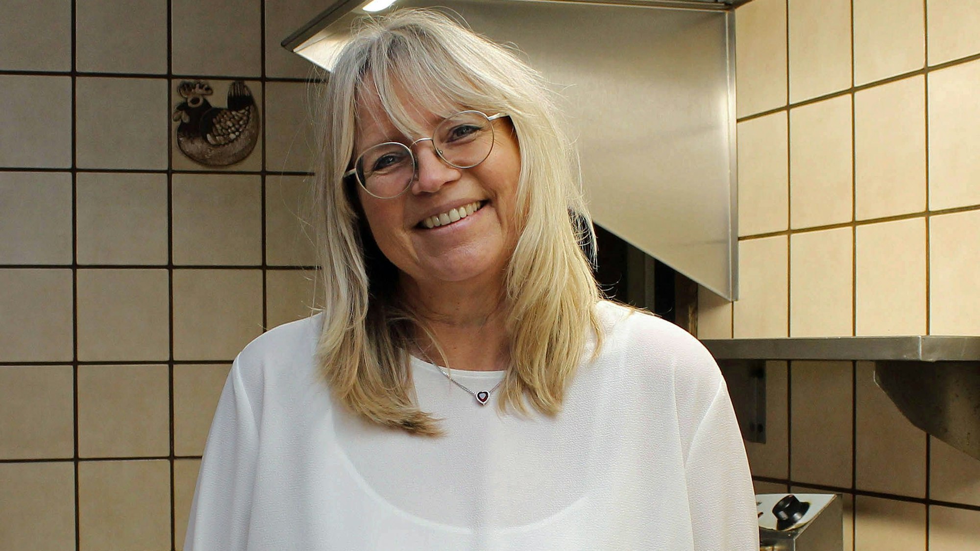 Sonja Grell steht vor weißen Kacheln.