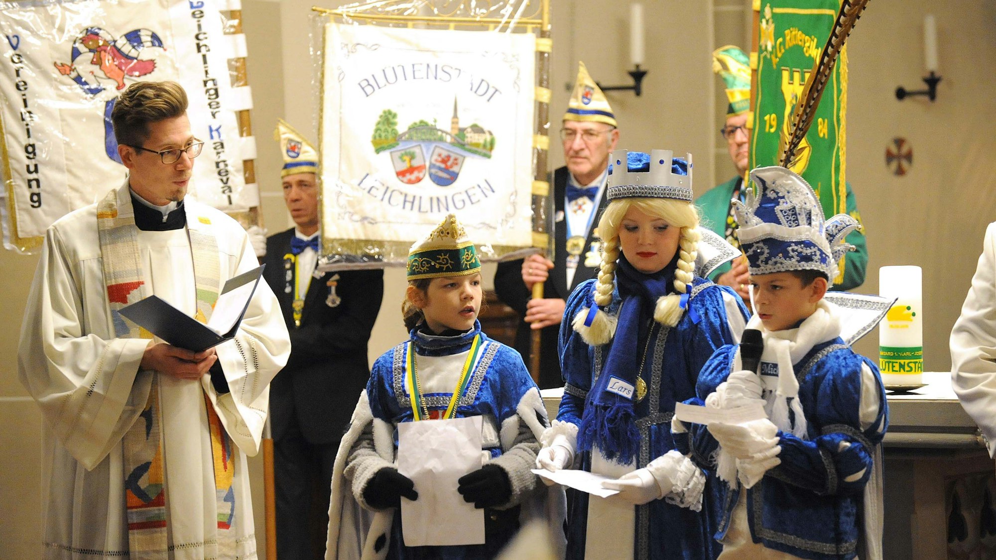 Pfarrer Michael Eichinger mit dem Kinderdreigestirn und Standartenträgern in der Kirche