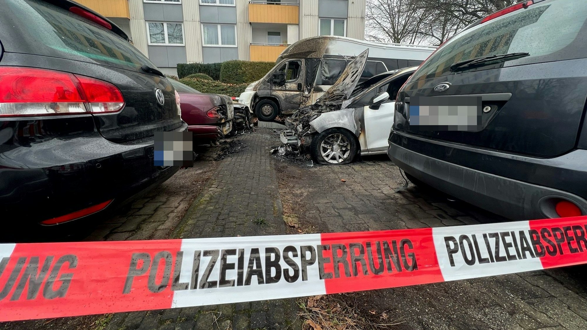 Mehrere ausgebrannte Autos auf einem Parkplatz in Köln-Porz.