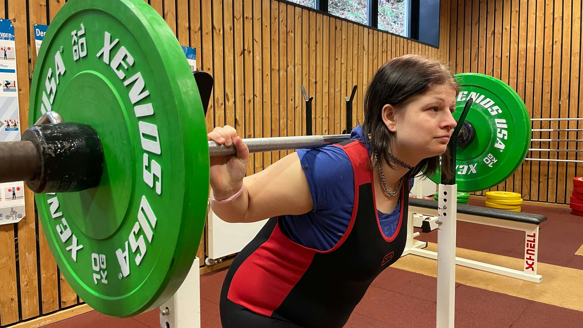 Behinderte Kraftsportlerin Jessica Steinbrück drückt eine Langhantel mit grünen Gewichten in die Höhe.
