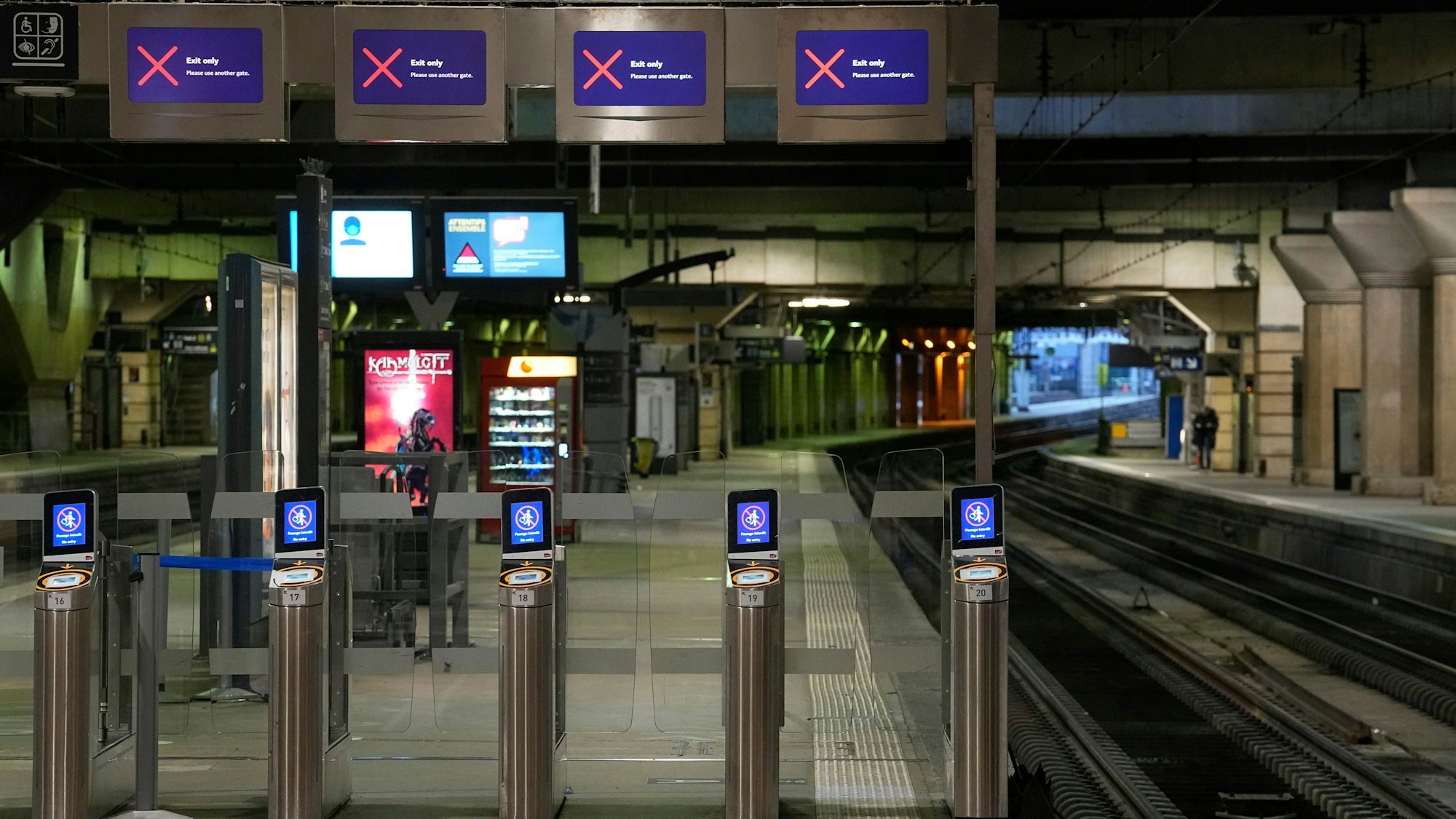 Verlassene Bahnsteige am Bahnhof Montparnasse in Paris. Zu sehen sind mehrere Ticketkontrollsysteme und Bildschirme, die ein rotes Kreuz zeigen.