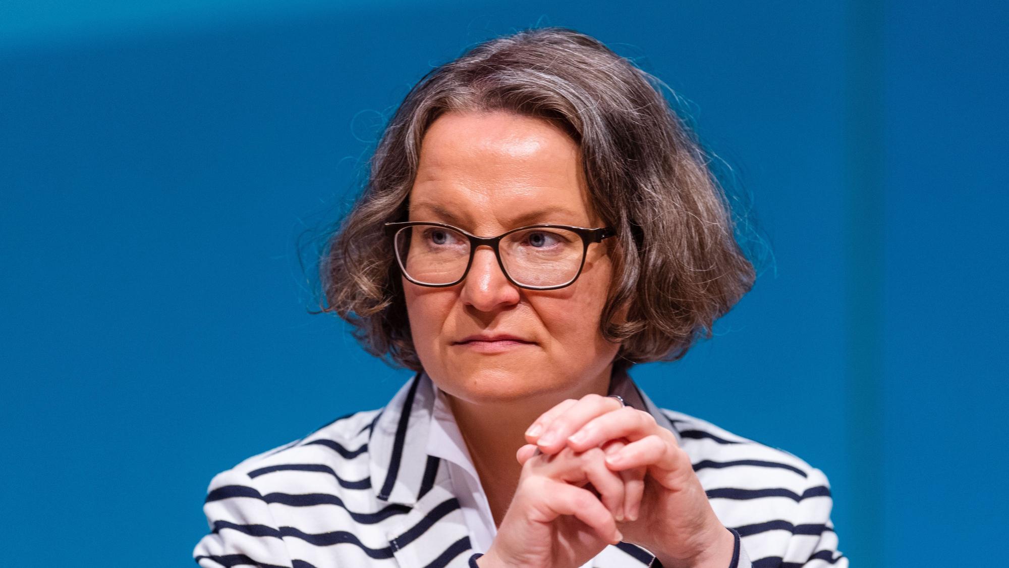 Das Foto zeigt Scharrenbach im Porträt. Sie trägt einen schwarz-weiß gestreiften Pulli und eine Brille.