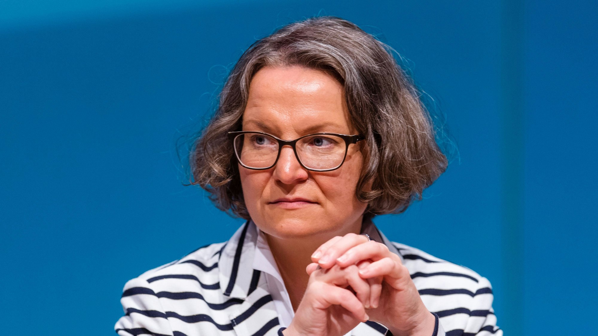 Das Foto zeigt Scharrenbach im Porträt. Sie trägt einen schwarz-weiß gestreiften Pulli und eine Brille.