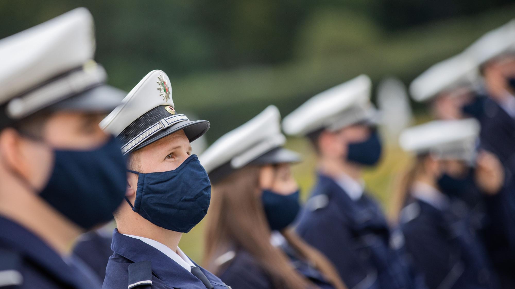 Kommissar-Anwärter und -Anwärterinnen tragen bei einer Vereidigungsfeier der Polizeien Köln, Bonn und Aachen Alltagsmasken.