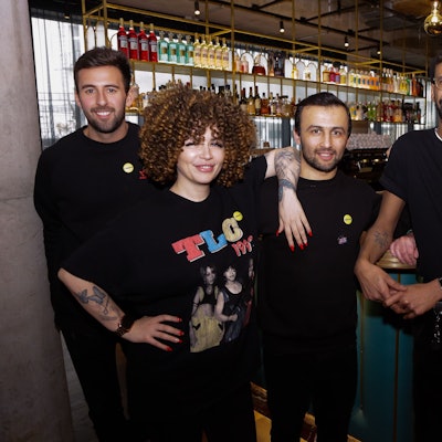 Der Hotelmanager Daniel Suré mit vier Mitarbeitern vor der Bar des Hotels. Eine Mitarbeiterin hat tätowierte Arme, ein Kollege ein Nasenpiercing und ebenfalls Tattoos.