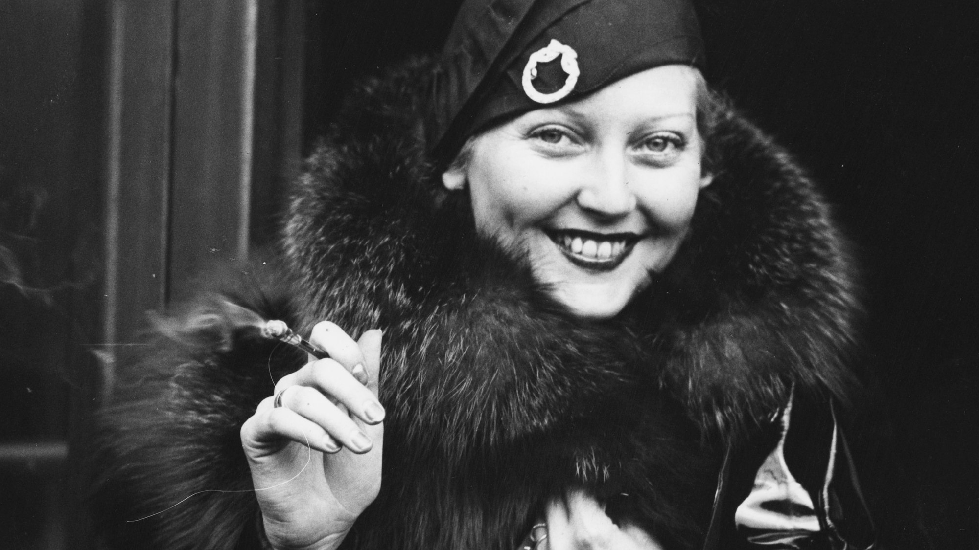 Thelma Tood mit Zigarillo vor einem Zug.