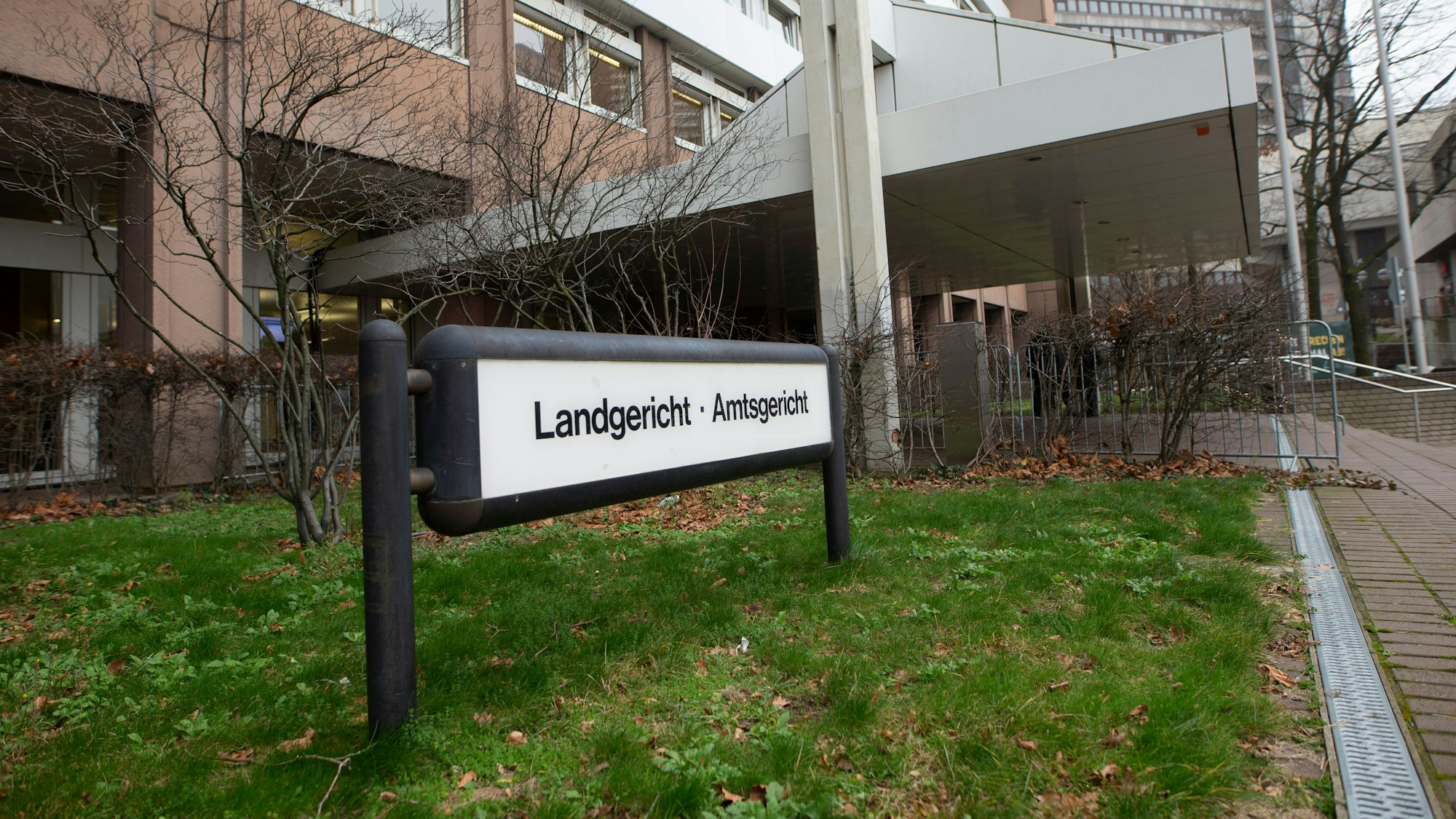 Vor dem Eingang zum Gerichtsgebäude in Köln steht ein Schild mit der Aufschrift „Landgericht – Amtsgericht“.