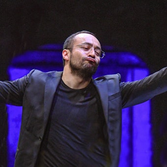 Das Bild zeigt den Dirigenten Riccardo Minasi 2018 - Generalprobe zur Aufführung des Bühnenstückes Mass von Leonhard Bernstein, im Festspielhaus in Salzburg. Minasi dirigiert und hat dabei die Arme ausgebreitet.