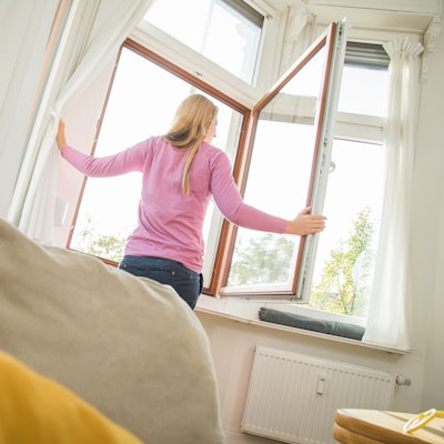 Eine Frau öffnet das Fenster, um ihre Wohnung zu lüften.